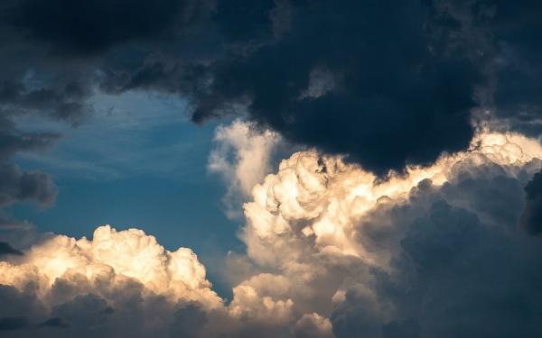 Dunkle und helle Wolken mit Sonnenstrahlen am Himmel