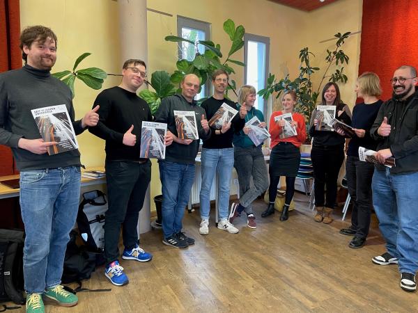 Gruppenbild der Beraterinnen und Berater der Mobilen Beratungsstellen mit der Jubiläumsbroschüre