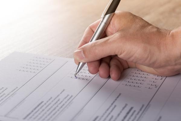 Umfragebogen, der von einer Person mit einem Stift ausgefüllt wird