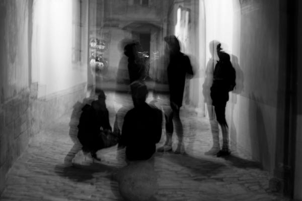 Schemenhafte Personen in einer Gasse in schwarzweiß