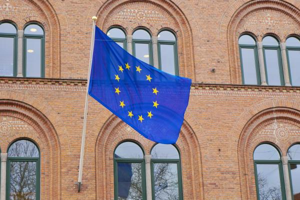 Eine europäische Flagge weht vor einem Backsteingebaude