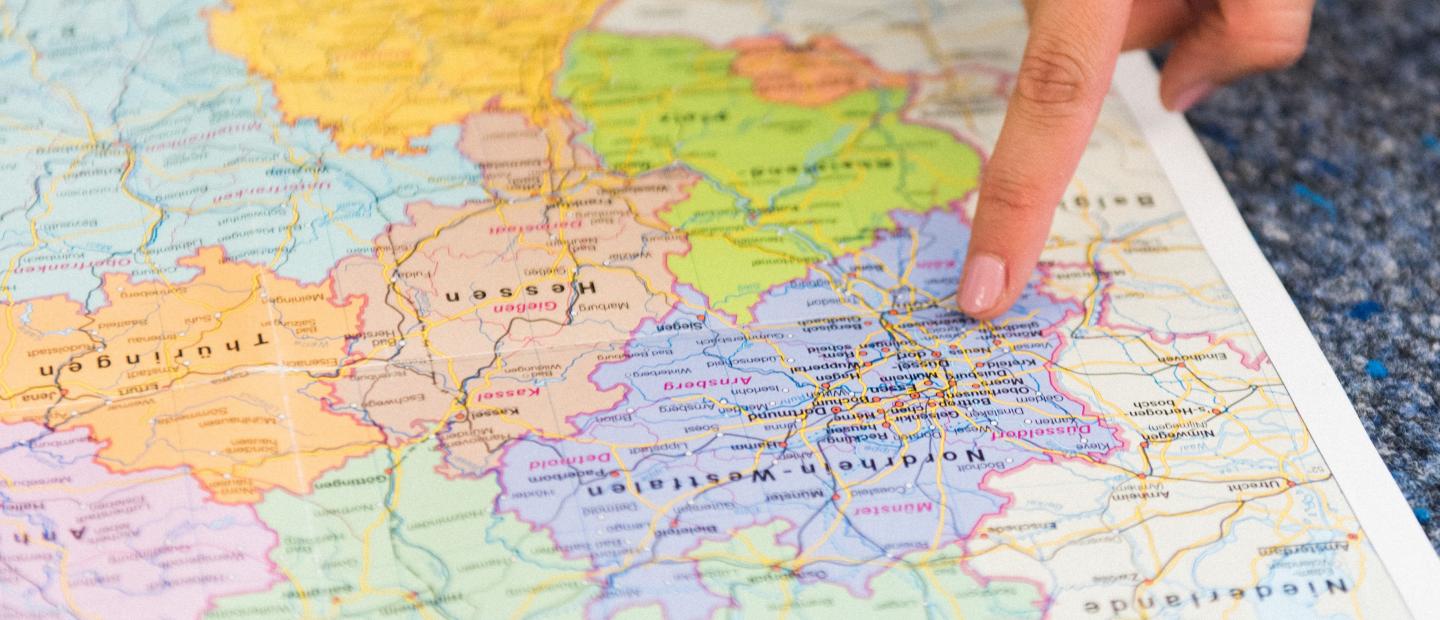 Ein Finger zeigt auf einer Landkarte das Bundesland NRW
