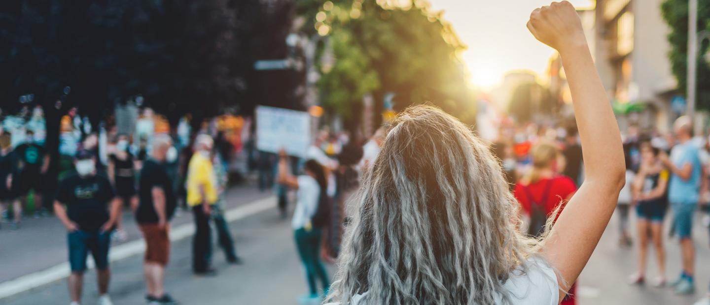 Rückansicht einer Frau auf der Straße, die eine Faust hebt